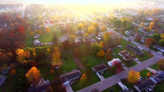 Scenic small town with bright,foggy Autumn sunrise, aerial flyover.
