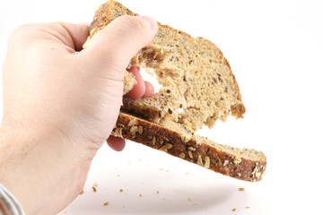 Man's hand crushing a slice of whole wheat bread
