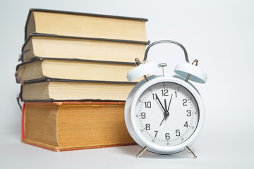 Alarm clock and books on white background