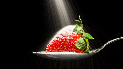 Sugar pouring over a strawberry on a spoon