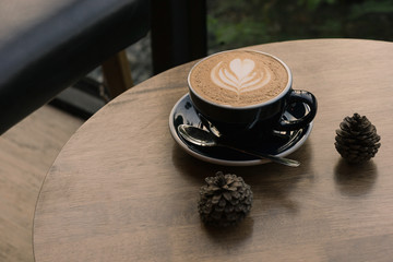 hot fresh coffee in white glass with tree shape of heart foam on wooden table at sunset at coffee time / hot fresh coffee