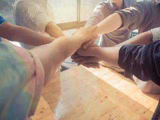 Group of people putting their hands working together on wooden b