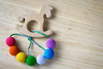Necklace made from knitted beads and wooden horse toy for the baby sitting in a sling. Knitted beads. Sling nursing necklace.