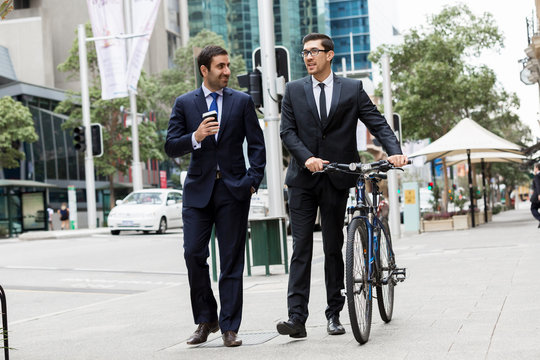 Two young businessmen with a bike in city centre