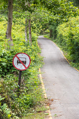 No car prohibit sign on walkway road in green forest