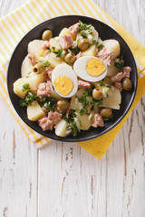 Spanish salad Patatas Alinadas of boiled potatoes with tuna, egg and olives close-up. Vertical top view