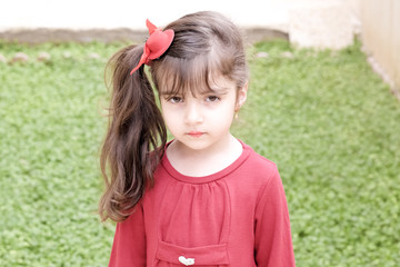 Small girl in red dress with garden in back