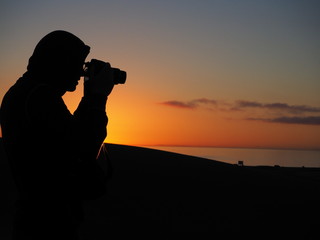 Man with camera at sunrise in dunes of Maspalomas Gran Canaria
