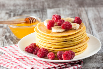 Fresh made delicious pancakes with berries, blackberries, raspberries, banana, honey and maple syrup. Healthy morning breakfast concept.