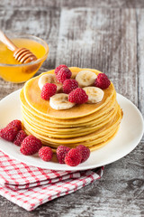 Fresh made delicious pancakes with berries, blackberries, raspberries, banana, honey and maple syrup. Healthy morning breakfast concept.
