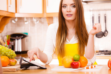 Woman housewife in kitchen using tablet