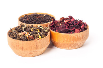 Dry tea in wooden plates, on white background. Leaves of red, green and black tea. Macro photo.