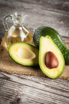 Close-up of an avocado and avocado oil on wooden table. Healthy food concept.