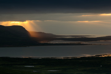 Storm sky with majestic golden rays of  setting sun over  sea. Arctic summer, the tundra, Norway.