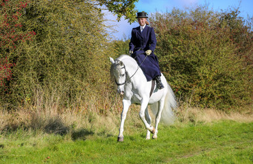 Girl riding white horse side saddle