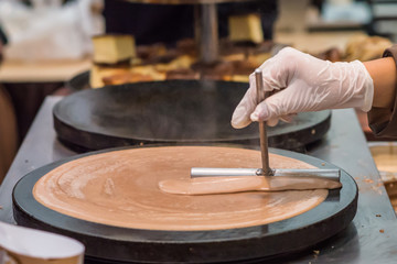 Obraz premium hand in gloves prepares chocolate pancake outdoors