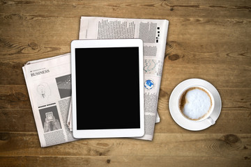 Daily newspaper and tablet with a blank screen on the wooden tab