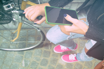 Girl using cellphone alongside with her bicycle.