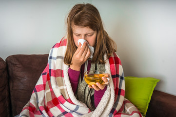 Sick young woman with fever drinking cup of warm tea