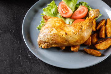 Roasted chicken legs with potato wedges and tomatoes