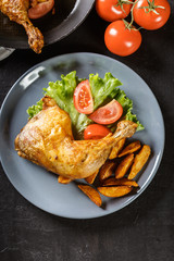 Roasted chicken legs with potato wedges and tomatoes