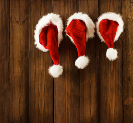 Obraz na płótnie Canvas Christmas Santa Claus Hats Hanging Xmas Family Clothing on Wood Wall