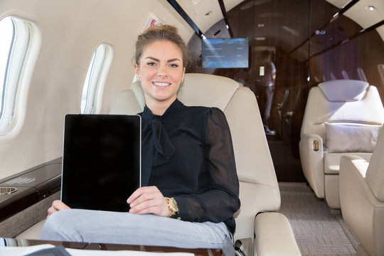 woman in corporate jet showing tablet computer