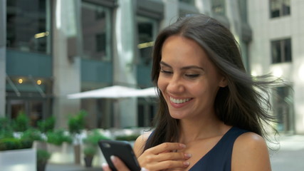 Attractive business woman commuter using smartphone walking in city