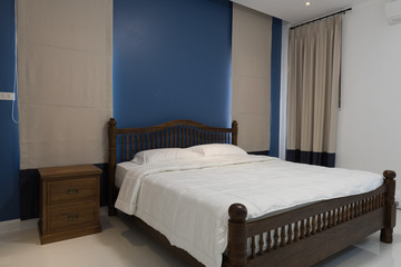 Modern blue bedroom with grey curtain and retro wooden side tabl