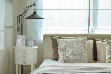 luxury bedroom with lamp and alarm clock on wooden table at home