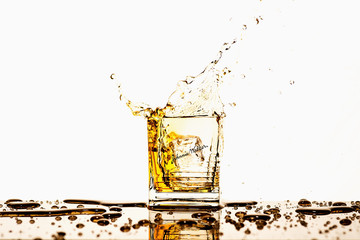 Produktfotos . Im Bild: Ein gefülltes Whiskey Glas in das ein Eiswürfel fällt und Flüssigkeit heraus spritz. 