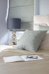 Glasses and book on bed with satin style bedding