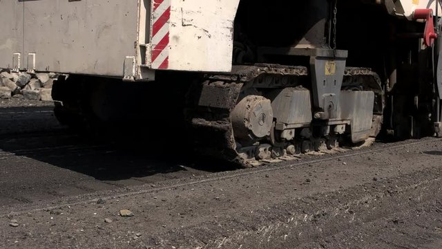 Cold milling machine. Slow movement of tracked vehicle. City roads need reconstruction. Building company bought new equipment.