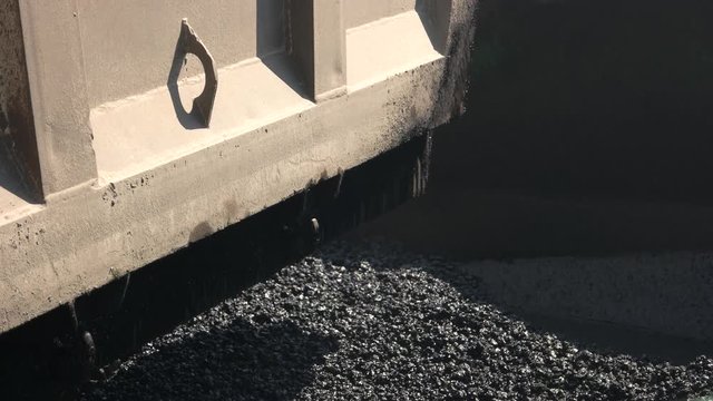 Pile of fresh asphalt. Dirty part of construction machine. Stones and tar. Build better roads.