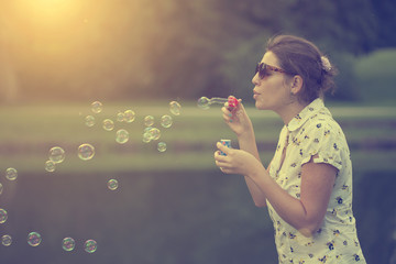 woman blowing soap bubbles in summer sunset