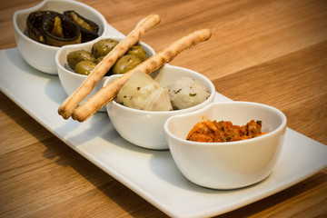 Antipasti in kleinen weißen, runden Schüsseln auf einem Holzbrett