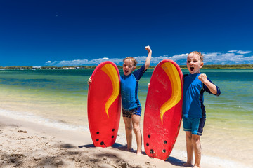 Young surfer brothers have fun on beach learning to surf