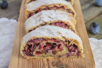 Front View on Plum strudel on wood plank timber with fresh plums