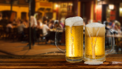 cold mug of beer with foam on the background of the street