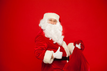 Portrait of Santa Claus with huge red sack thumb looking at camera