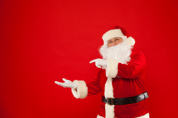 Fototapeta na wymiar Santa Claus pointing in blank a place, red background