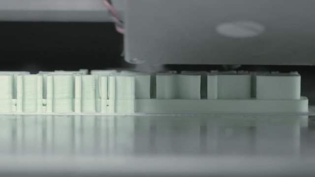 Extreme close-up view of mechanism of 3d printer making pieces with white plastic. Innovation in printing process