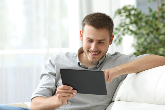 Man using a tablet on a couch at home