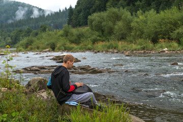 Fototapeta premium Man plays a hang drum near the river. Carpathians. Ukraine.