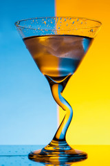 Glass with water over blue and yellow background.