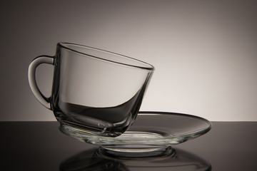 Glass empty mug of tea and saucer on a black and white backgroun