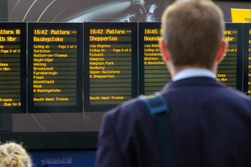 Naklejka premium Dojeżdżający do pracy sprawdzający cyfrowy rozkład jazdy na stacji kolejowej