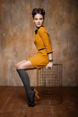 Beautiful young girl sits on a bird cage