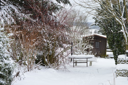 Verschneiter Garten mit Bank und Gartenhaus