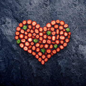 Strawberry heart / Valentine and love concept, creative still life of heart made of sliced strawberries, on stone background.